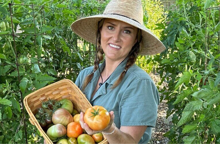 Garden educator Callie Works-Leary holding a basket of heirloom tomatoes in her DFW North Texas garden.